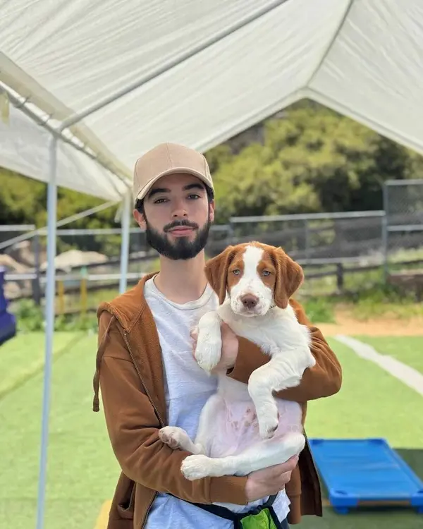 Oliver holding a brown and white spaniel puppy in the training yard