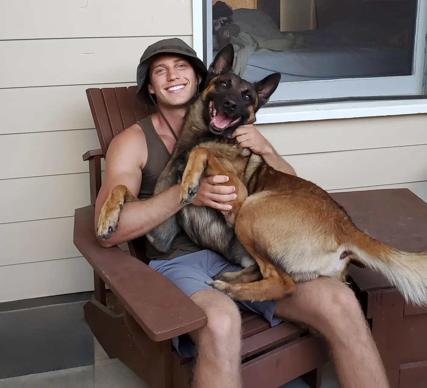 Davin, our lead trainer, sitting with a happy Malinois in his lap